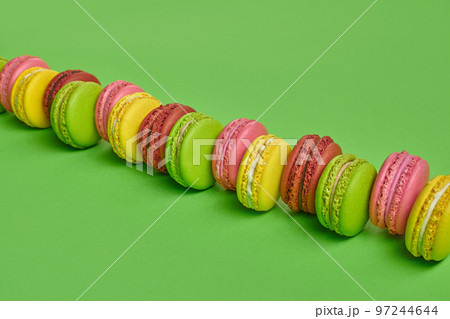 Colored macaron or macaroon, sweet meringue-based confection on green background. Close-up, copy space. Colored macaron or macaroon, sweet meringue-based confection on green background. Close-up, copy space. 97244644