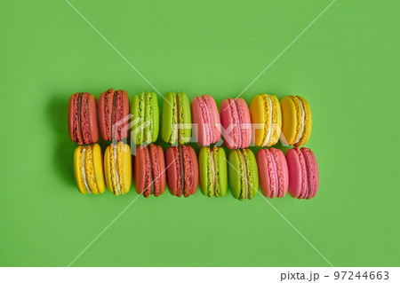 Colored macaron or macaroon, sweet meringue-based confection on green background. Close-up, copy space. 97244663