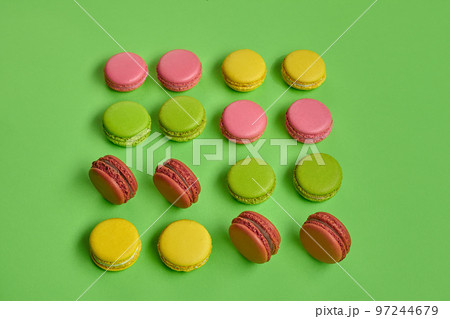 Colored macaron or macaroon, sweet meringue-based confection on green background. Close-up, copy space. Colored macaron or macaroon, sweet meringue-based confection on green background. Close-up, copy space. 97244679