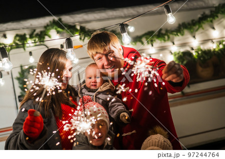 Happy large family celebrates christmas in nature and holds sparklers. Parents with three sons travels in a mobile home. Happy large family celebrates christmas in nature and holds sparklers. Parents with three sons travels in a mobile home. 97244764