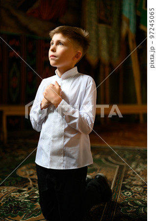 The boy is kneeling in prayer to God. The boy is kneeling in prayer to God. 97245065