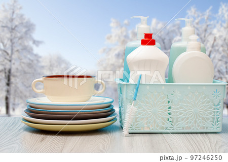 Bottles of dishwashing liquid and plates with winter on background. Bottles of dishwashing liquid and plates with winter on background. 97246250