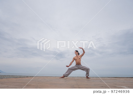 Caucasian man practices martial arts outdoors. balance and meditation. Caucasian man practices martial arts outdoors. balance and meditation. 97246936