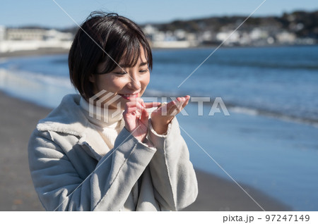 冬の砂浜で貝殻を拾う女性 冬の砂浜で貝殻を拾う女性 97247149
