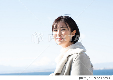 冬の海をバックに笑顔の女性 冬の海をバックに笑顔の女性 97247293