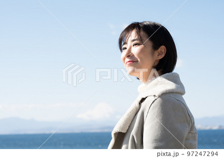 冬の海をバックに笑顔の女性 97247294