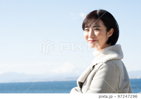 冬の海をバックに笑顔の女性 97247296