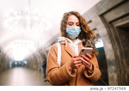 Girl in protective sterile medical mask on her face at empty subway station. Woman, wear face mask 97247569