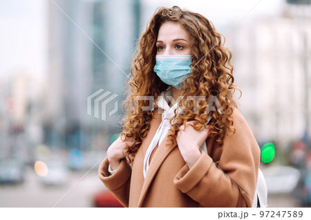 Woman in protective medical mask on her face on the street. Woman, wear face mask. Corona virus. Woman in protective medical mask on her face on the street. Woman, wear face mask. Corona virus. 97247589