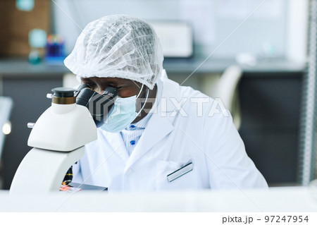Black man looking in microscope and working on research in lab 97247954