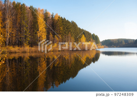 Colorful foliage tree reflections in calm pond water on autumn day. Colorful foliage tree reflections in calm pond water on autumn day. 97248309