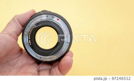 Close-up of a man holding a camera lens in his hand on a background Close-up of a man holding a camera lens in his hand on a background 97248312