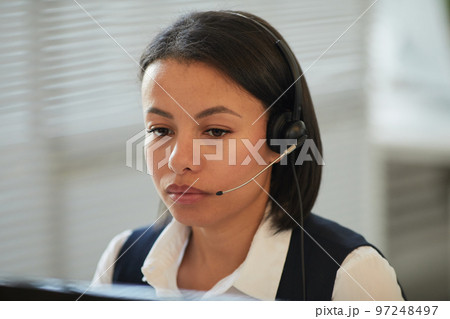 Woman wearing headset and looking at computer screen 97248497