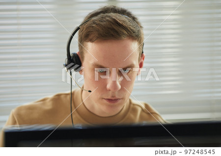 Young man wearing headset in tech support office Young man wearing headset in tech support office 97248545