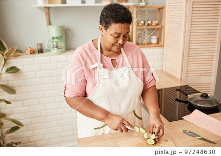 Black senior woman cutting vegetables 97248630
