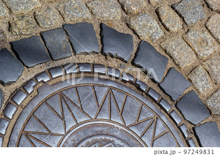 Old metal sewer hatch in the middle of the road, laid out of a smooth paving stone 97249831