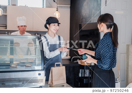 お菓子屋さんでクレジットカード決済をする女性 お菓子屋さんでクレジットカード決済をする女性 97250246