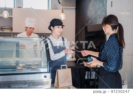 お菓子屋さんでクレジットカード決済をする女性 97250247