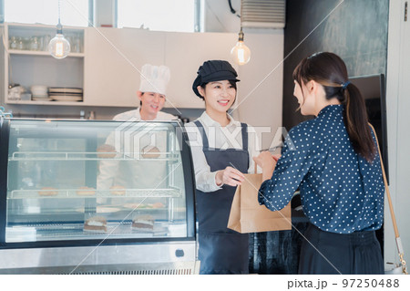 こだわりのお店でテイクアウトをする若い女性 97250488