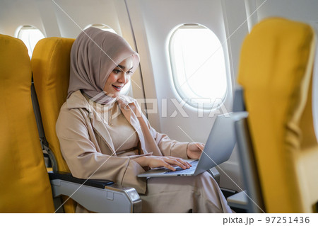 Beautiful asian muslim business woman working on digital laptop computer during the flight for her business trip. Business and transportation concept 97251436
