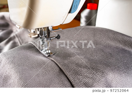 Modern sewing machine and gray fabric. Sewing process, handmade, hobby, DIY, business, repair Modern sewing machine and gray fabric. Sewing process, handmade, hobby, DIY, business, repair 97252064