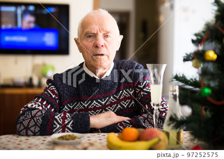 Portrait of elderly man at table enjoying glass of wine at Christmas 97252575