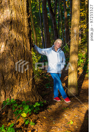 Attractive blonde woman walking in the forest on a nature hike. Attractive blonde woman walking in the forest on a nature hike. 97255527