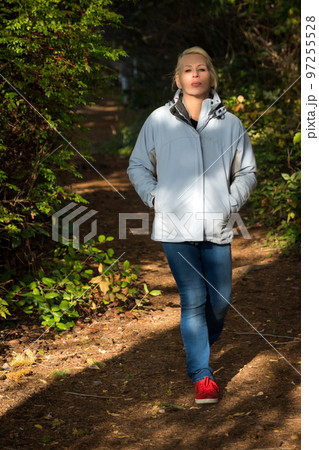 Attractive blonde woman walking in the forest on a nature hike. 97255528