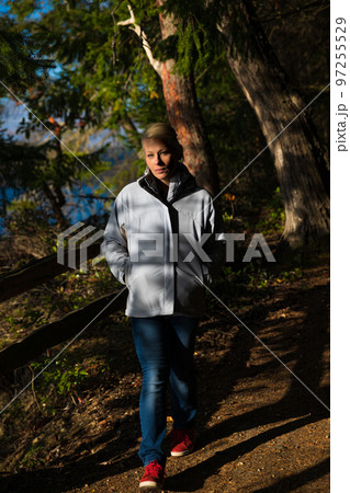 Attractive blonde woman walking in the forest on a nature hike. Attractive blonde woman walking in the forest on a nature hike. 97255529