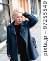Fashionable blonde woman walking exploring the city. 97255549