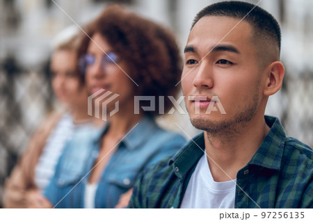 Cute pensive young man in the company of women Cute pensive young man in the company of women 97256135
