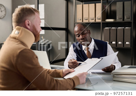 Portrait of black insurance broker helping man with neck brace filling legal forms after accident Portrait of black insurance broker helping man with neck brace filling legal forms after accident 97257131