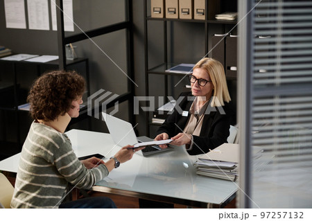 High angle view at woman with neck brace handing documents to attorney or insurance broker after accident High angle view at woman with neck brace handing documents to attorney or insurance broker after accident 97257132