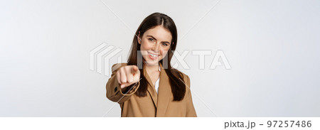Portrait of smiling enthusiastic businesswoman, saleswoman pointing finger at camera and choosing, inviting you, standing over white background 97257486