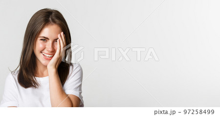 Close-up of beautiful smiling woman looking coquettish at camera over white background 97258499
