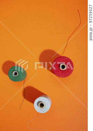 Three coils with colored threads on a colored background 97259327