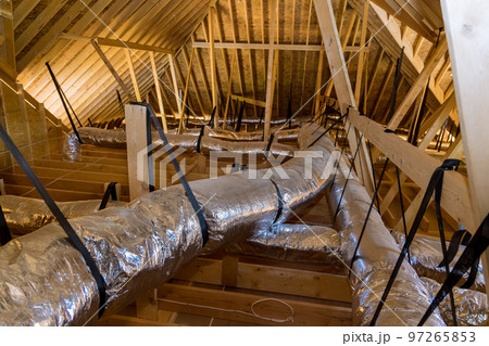 In newly built home under construction ventilation pipes are silver insulation material on ceiling of attic 97265853