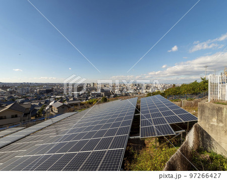 山の斜面に造成された太陽光発電施設と街の風景 97266427