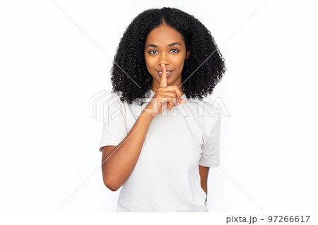 Pleased multiracial woman pressing finger to lips 97266617