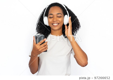 Portrait of happy young woman listening to music online on phone Portrait of happy young woman listening to music online on phone 97266652
