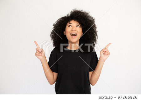 Amazed young woman pointing above at copyspace Amazed young woman pointing above at copyspace 97266826