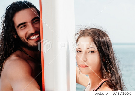 Woman man sea sup. Close up portrait of beautiful young caucasian woman with black hair and freckles looking at camera and smiling. Cute woman portrait in a pink bikini posing on sup board in the sea. 97271650