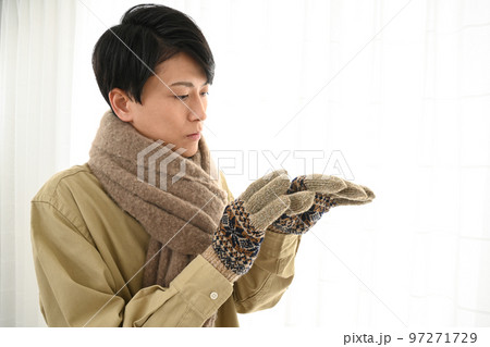 マフラーと手袋をする若い男性 97271729