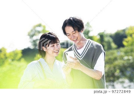 スマホで検索する若い夫婦 97272849