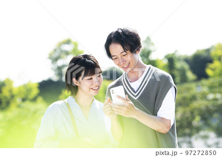 スマホで検索する若い夫婦 97272850