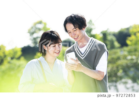 スマホで検索する若い夫婦 97272853