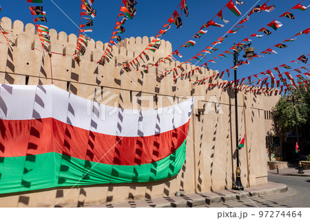 Oman national flag during Independence Day. Traditional medieval architecture in Nizwa, Oman.  97274464