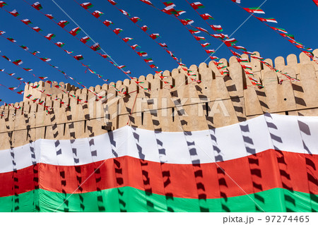 Oman national flag during Independence Day. Traditional medieval architecture in Nizwa, Oman.  97274465
