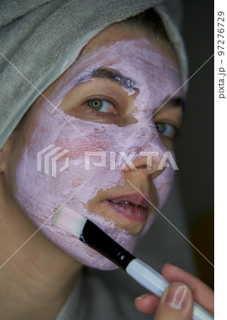 Woman with a towel over your head inflicts brush face mask of therapeutic clay. 97276729