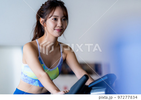 スポーツジムでトレーニングする若い女性 スポーツジムでトレーニングする若い女性 97277834